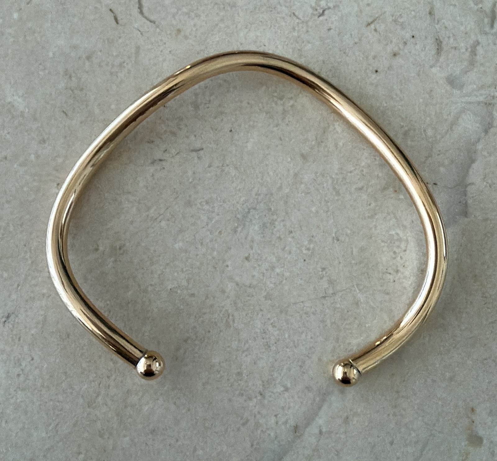 Pulseira aro com um leve ondulado no banho de ouro.