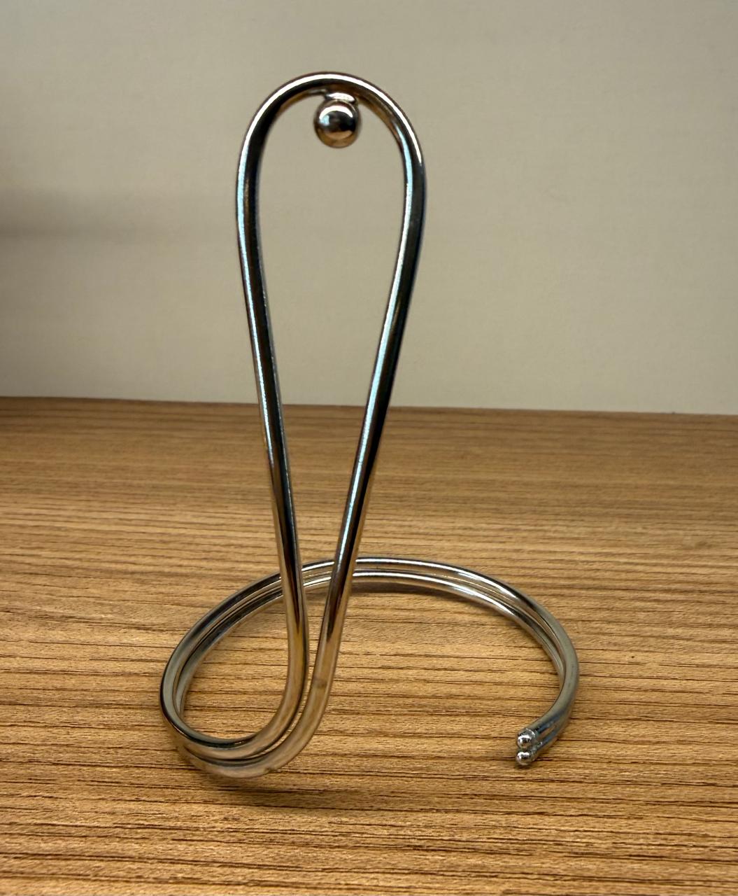 Pulseira aro no ródio branco com detalhe de uma volta comprida para frente ou para trás.