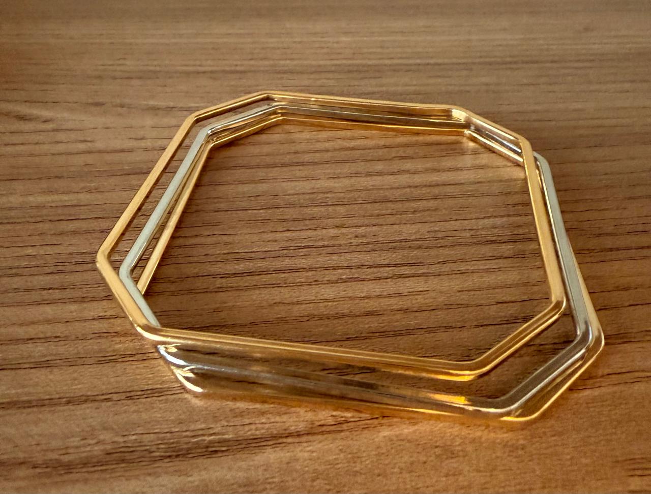 Trio de pulseiras , modelo aro geométrico fechado, duas no banho de ouro e uma no ródio branco.