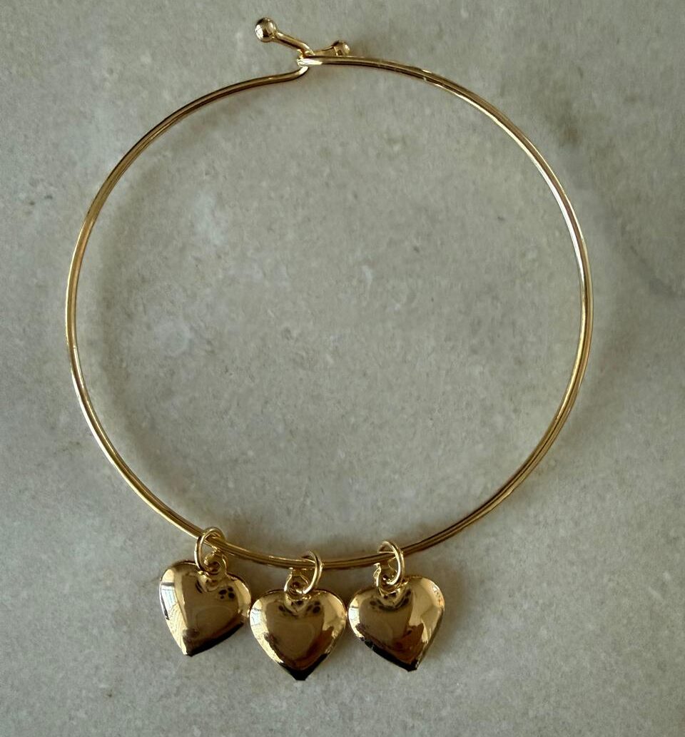 Pulseira aro fino com fecho com três pingentes de corações pendurados.