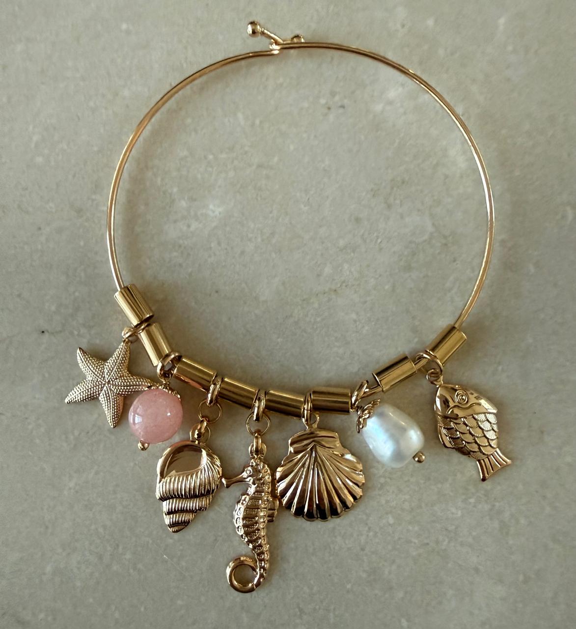 Pulseira aro fino com fecho, com pingentes , canutilhos entre um e outro. Pingentes no banho de ouro, uma pedra natural e uma pérola Barroca.