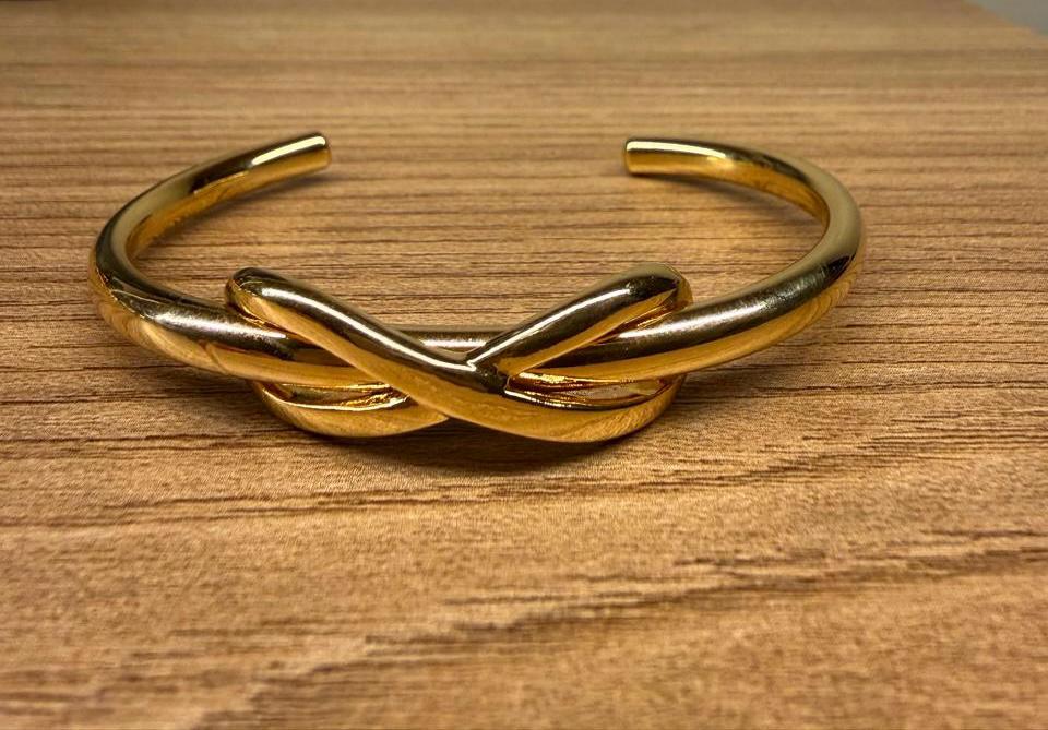 Pulseira aro tubo aberto com um detalhe tipo laço sem ponta.