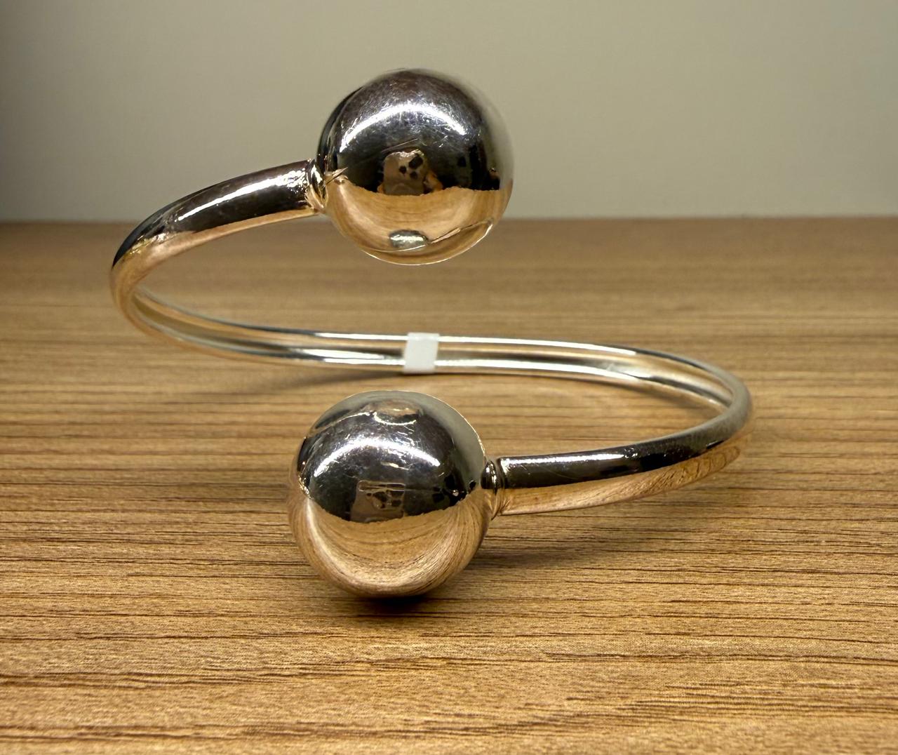 Pulseira aro aberto com duas bolas, uma em cada ponta. Peça no ródio branco.