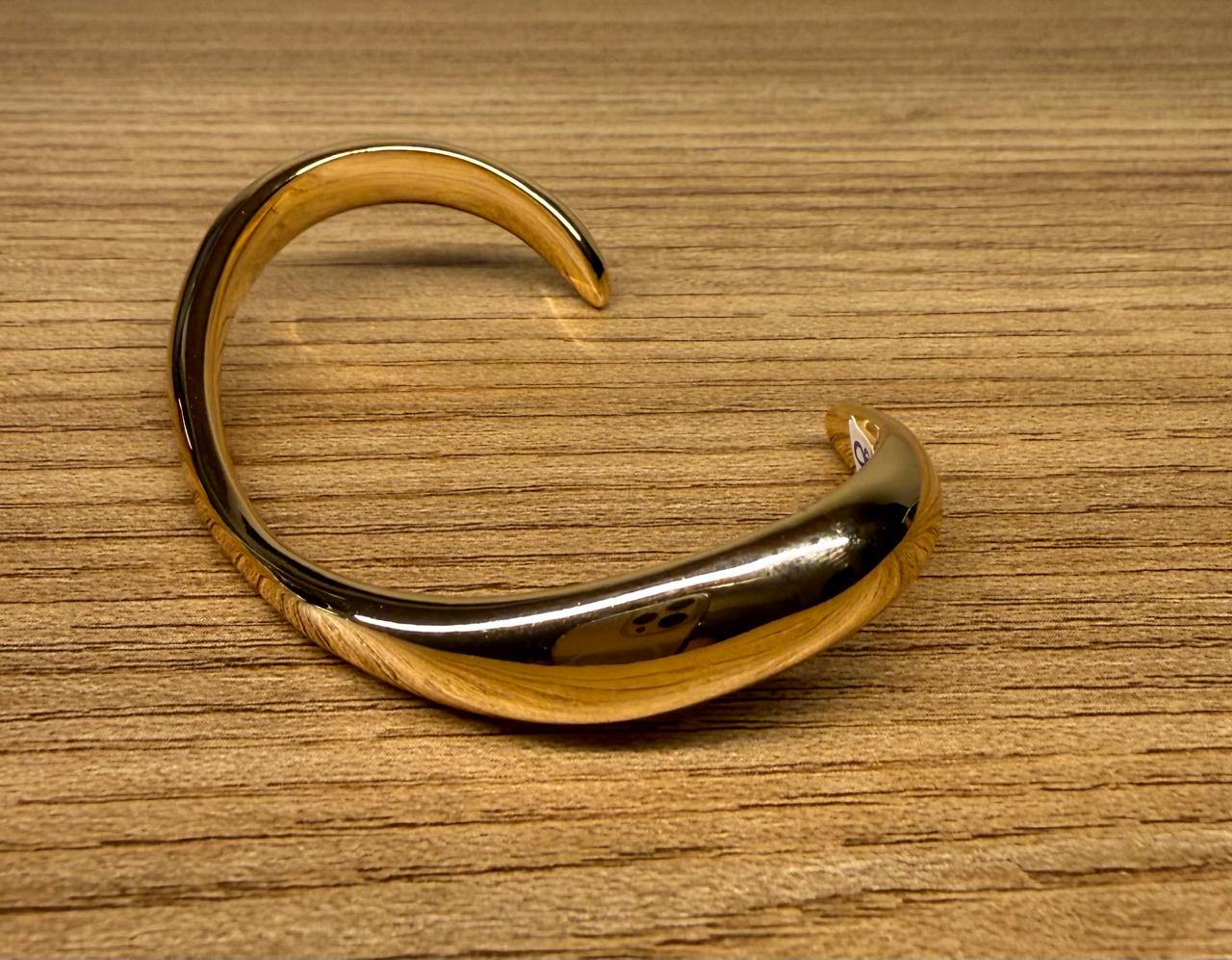 Pulseira aro aberto, fino em cima e largo nas laterais, abaulado. Sem fecho