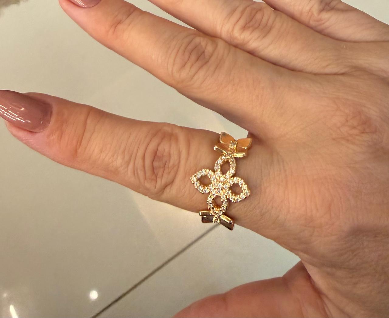 Anel regulável com três flores, uma cravejada de micro Zircônias e duas lisas com o miolo com uma mini zircônia.