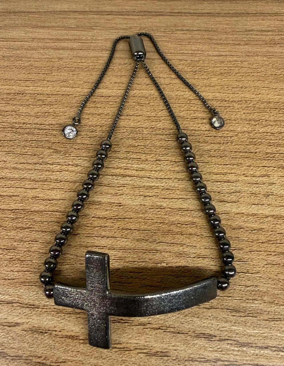 Pulseira regulável no banho negro, com uma cruz em cima e corrente de bolinhas.