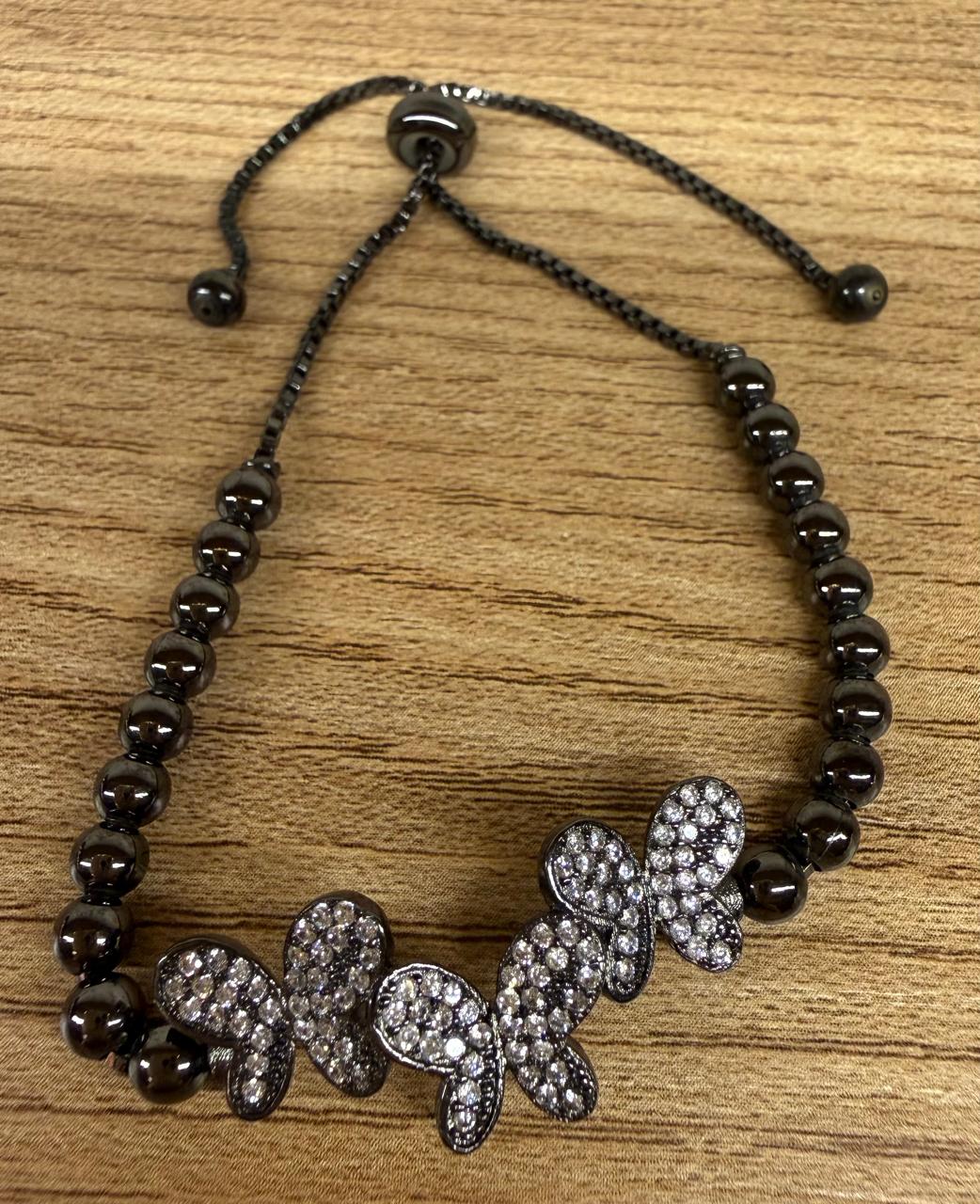 Pulseira regulável no banho negro ,com três borboletas cravejadas em cima e corrente de bolinhas.
