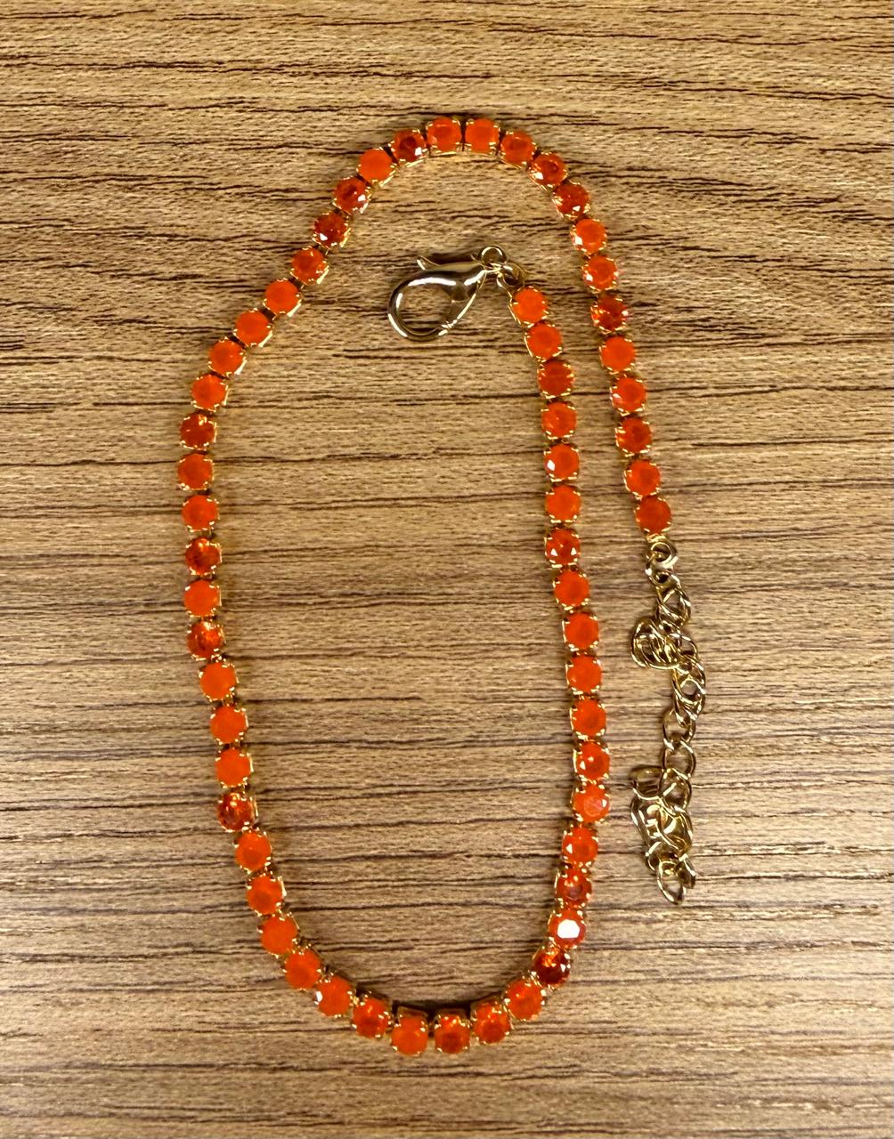 Tornozeleira no modelo Riviera com Zircônias na cor laranja. 23cm mais 5cm de extensor.