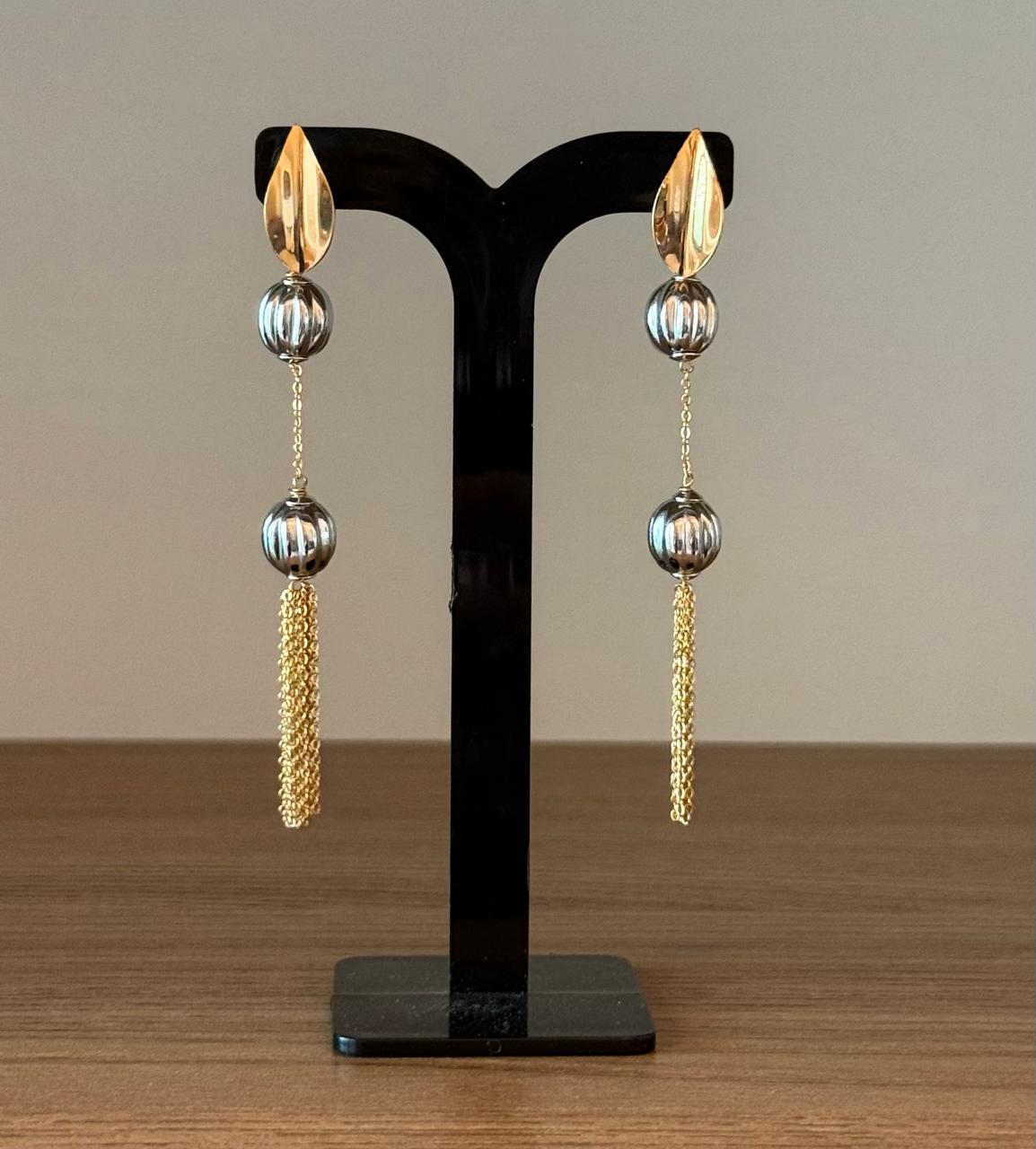 Brinco dois banhos com bolas trabalhadas e correntinhas dependuradas.