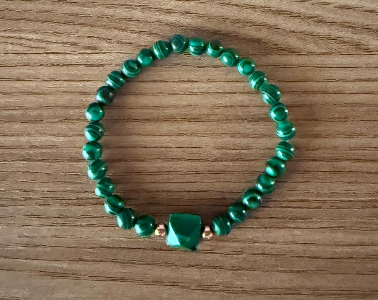 Pulseira elástica toda de bolinha na pedra Malaquita, com um detalhe de uma pirâmide na mesma pedra entre bolinha no banho rosê.