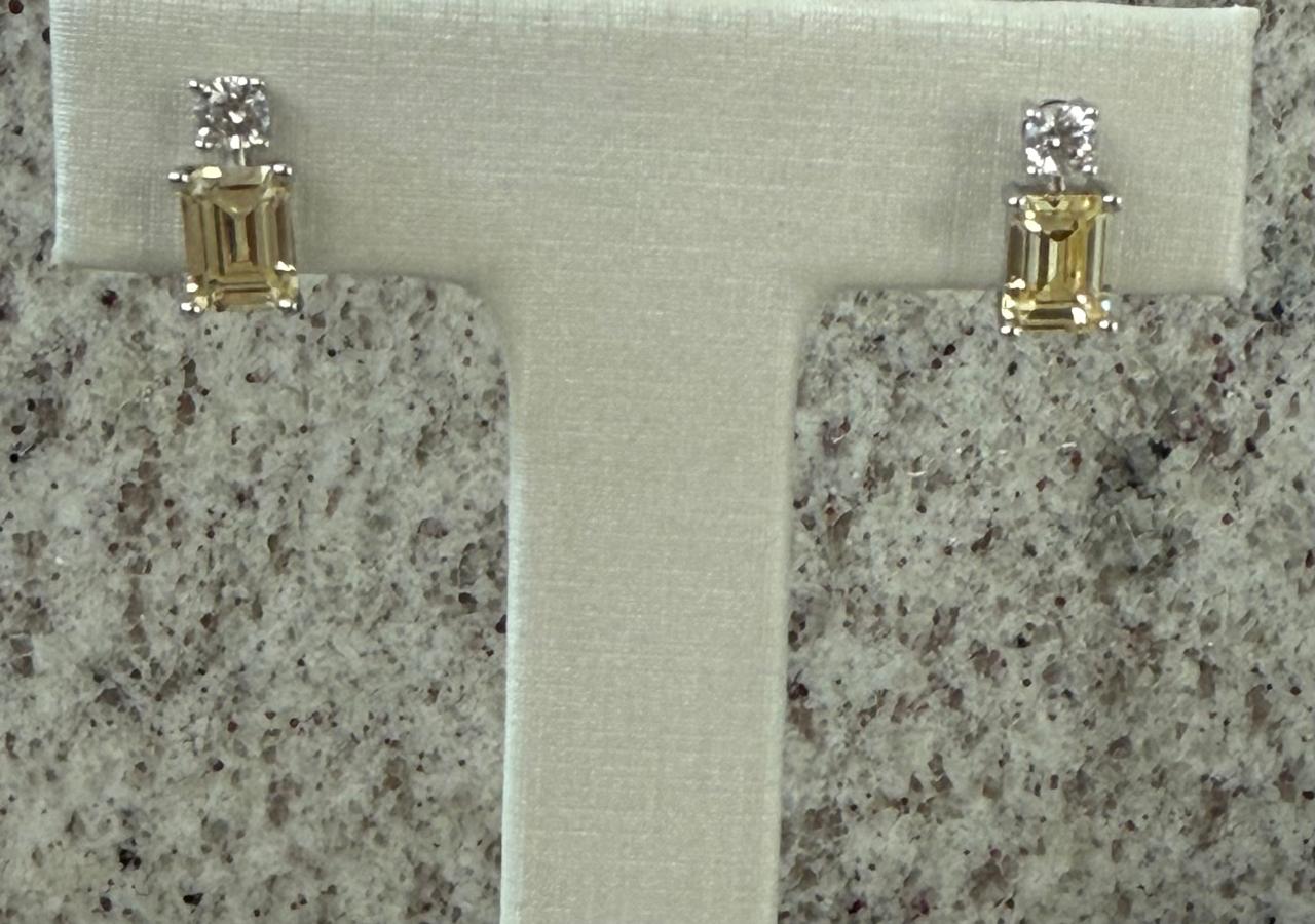 Brinco pequeno no ródio, uma zircônia com uma pedra lapidada em formato de retângulo amarelo clarinho.