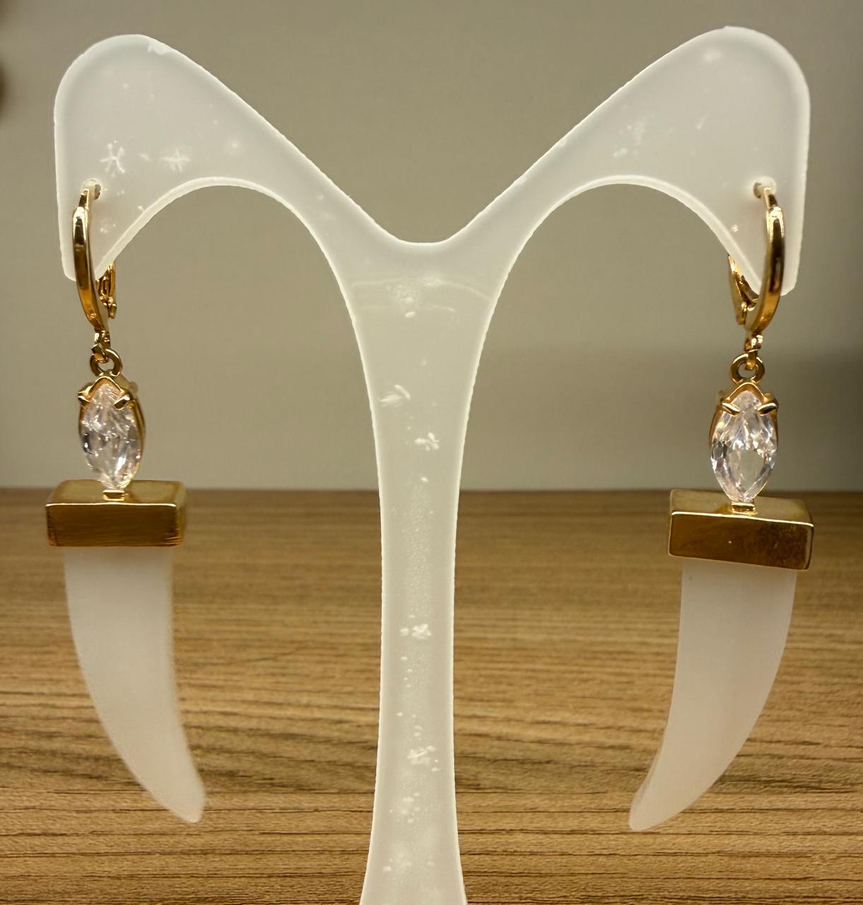 Brinco argolinha com uma pedra cristal oval com um dente madrepérola pendurado.